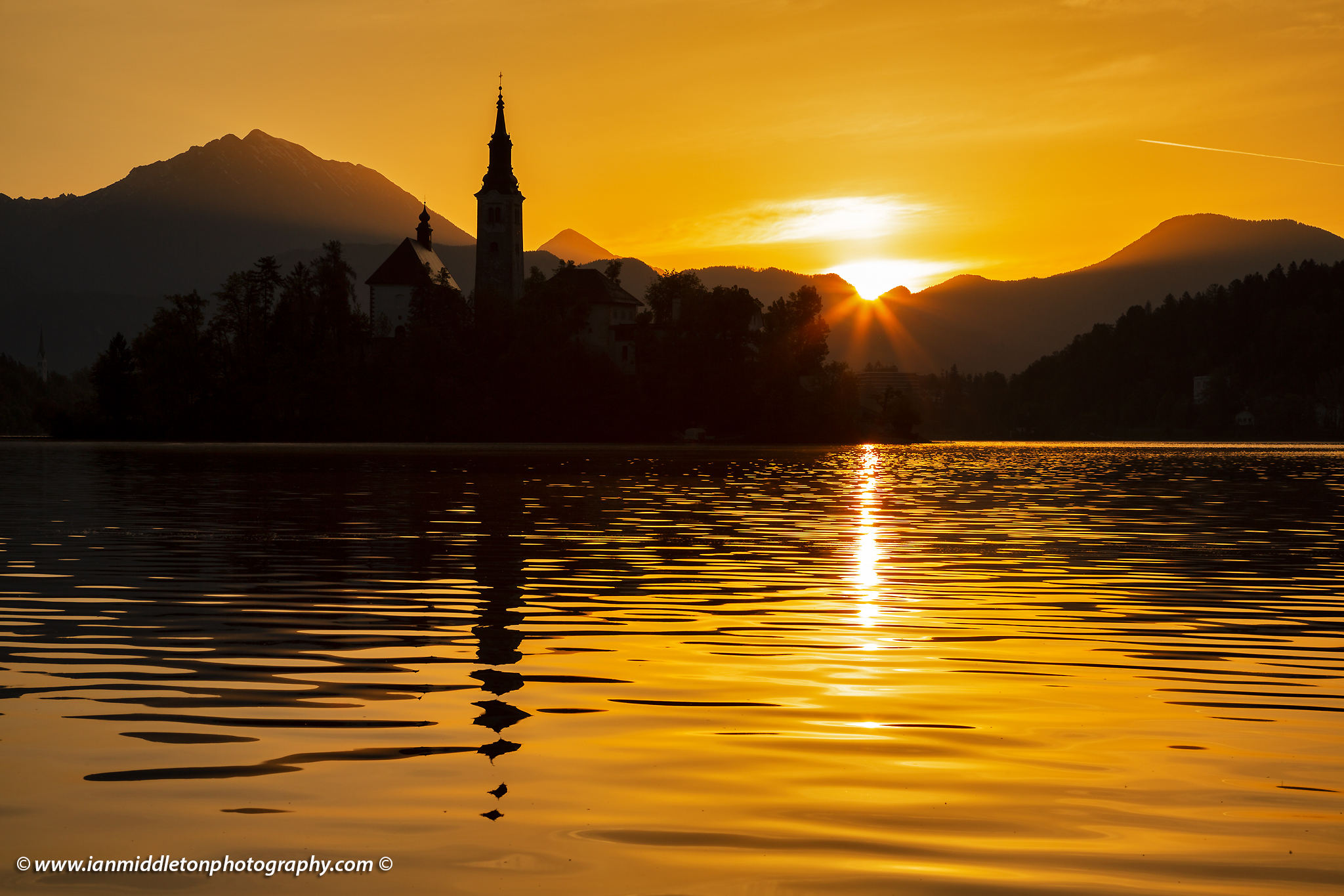 Sun rising over Lake Bled and the island church of the assumption of Mary with the Karavanke mountains in the background, Slovenia.