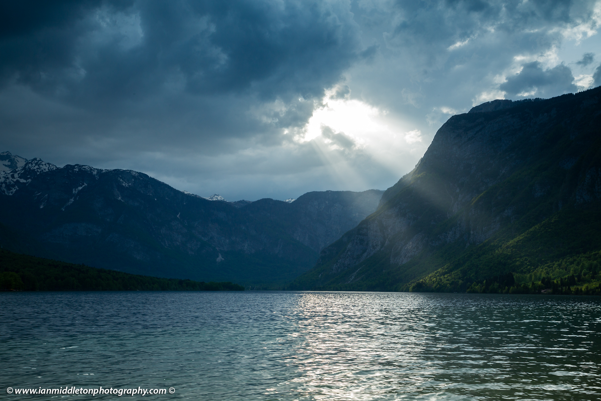 Sunlight breaking through clouds over the Julian Alps at Lake Bohinj, Triglav National Park, Slovenia
