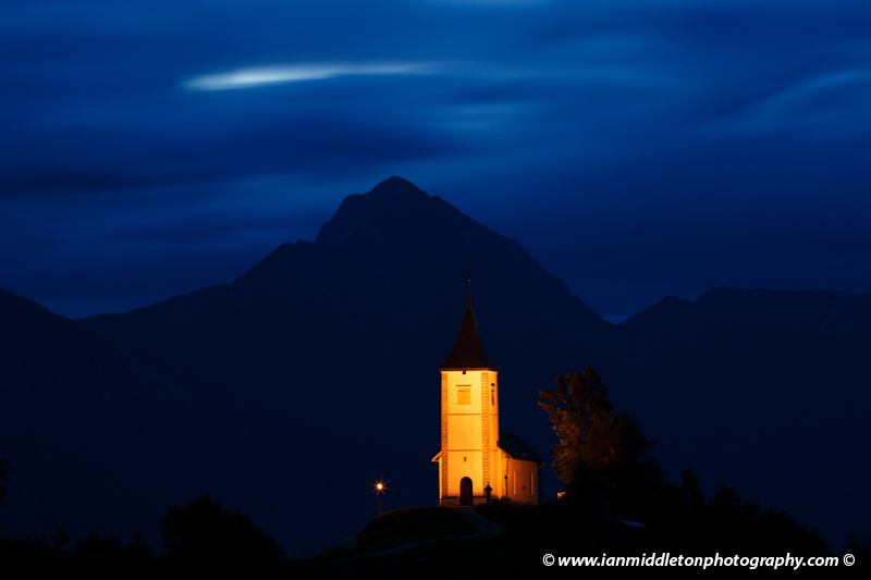 Jamnik church of Saints Primus and Felician at dawn, perched on a hill on the Jelovica Plateau with the kamnik alps and storzic mountain in the background, Slovenia.
