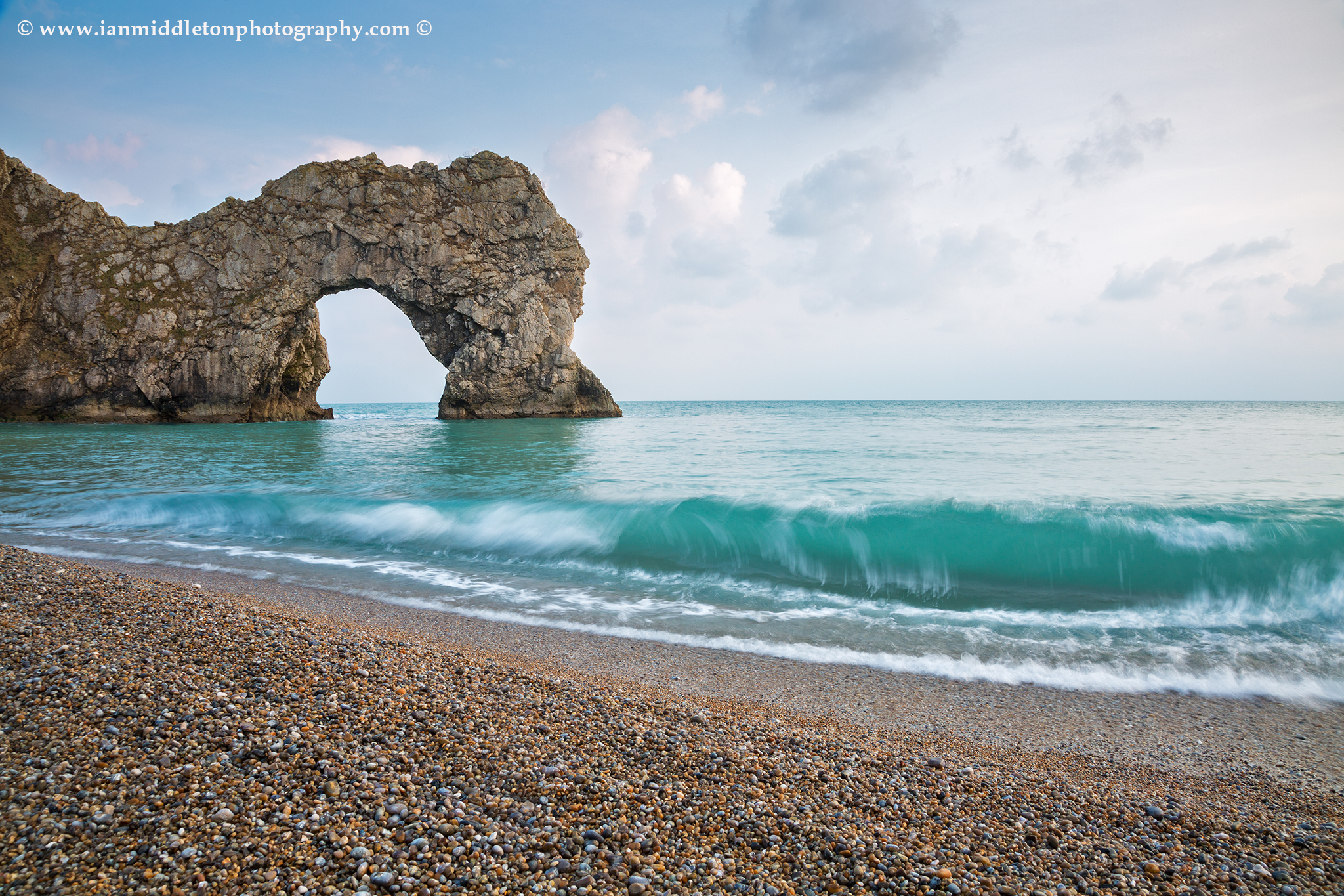 The late afternoon sun casts a warm glow over Durdle Door rock arch and beach, Dorset, England. Durdle door is one of the many stunning locations to visit on the Jurassic coast in southern England.