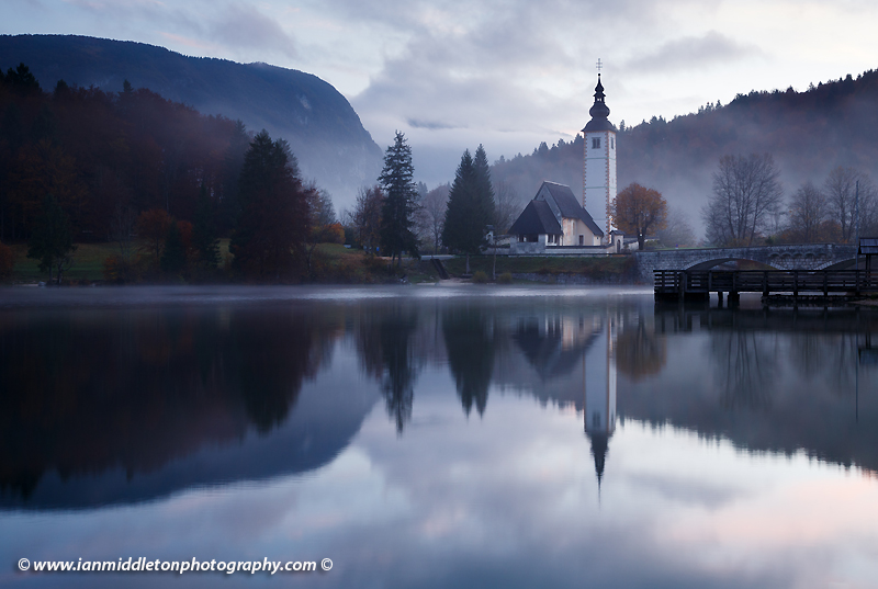 Morning mist and cloud over Lake Bohinj and the Church of Saint John at sunrise, Triglav National Park, Slovenia