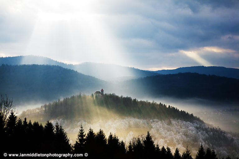 Afternoon sunrays falling over the church of Sveti Josef (Saint Joseph) seen from the church of Saint Anna (Sveta Ana). Sveta Ana is perched upon an exposed hill overlooking the Ljubljansko Barje (Ljubljana marsh) near the village of Preserje.