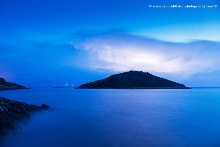 Lightning at dawn over the two small islands of Veli Osir and Mali Osir on Losinj Island, Adriatic Sea, Croatia. Photographed from Zaosiri beach near the village of Cunski, the main storm belt was primarily over the Istra peninsula but Losinj got the edge of it during the night. This was photographed as the storm moved southeast away from the Island.