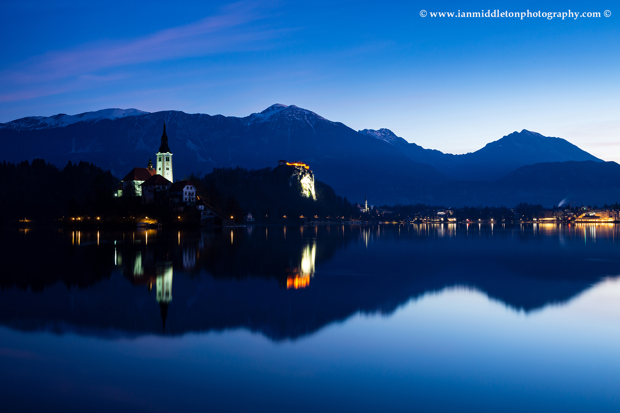 Dawn view across the beautiful Lake Bled, island church of the assumption of Mary, and hilltop castle, Slovenia.