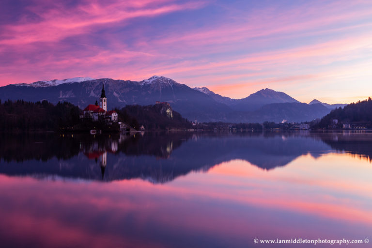 Sun rising over Lake Bled and the island church of the assumption of Mary with the Karavanke mountains in the background, Slovenia.