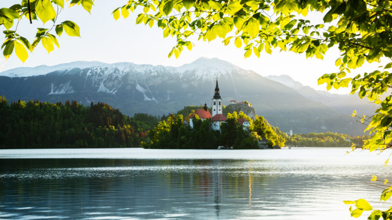 View across Lake Bled to the island church, clifftop castle and Mount Stol in all it's spring glory, Slovenia.