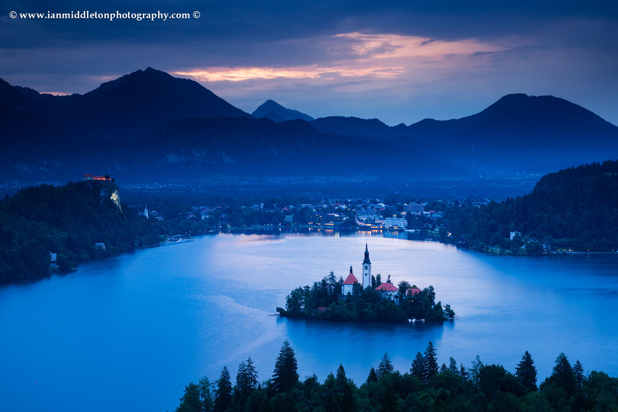 View across Lake Bled to the island church and clifftop castle from Ojstrica, Slovenia.
