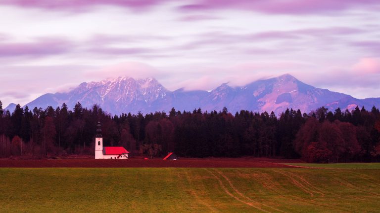 Sunset at the church of Saint James in the little village of Hrase, near Medvode in Gorenjska, Slovenia, with Mount Storzic of the Kamnik Alps peaking through the clouds behind.