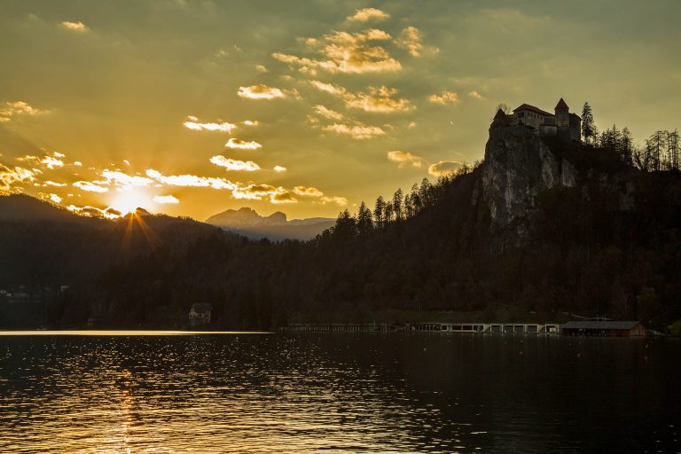 Sunset over Triglav Mountan beside the hilltop castle and the rest of the Julian Alps at Lake Bled, Slovenia.