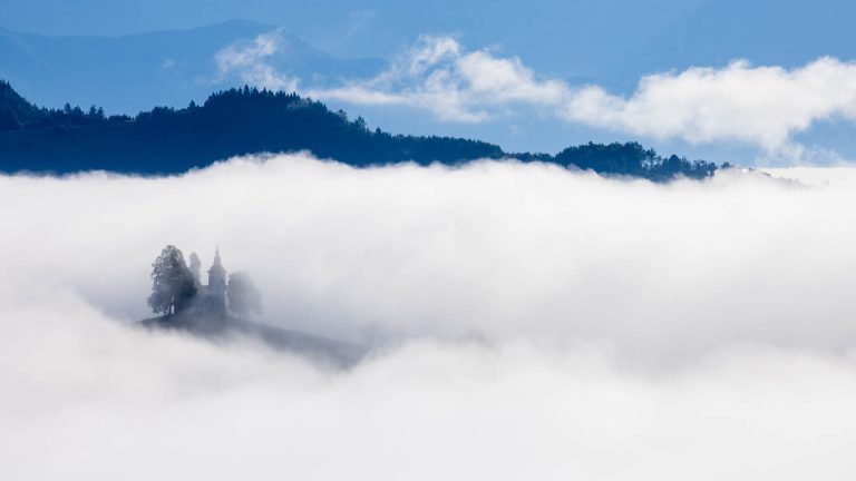 View from Rantovše hill across to Sveti Tomaz nad Praprotnim (church of Saint Thomas) as it appeares out of the thick morning mist in the Skofja Loka hills, Slovenia.