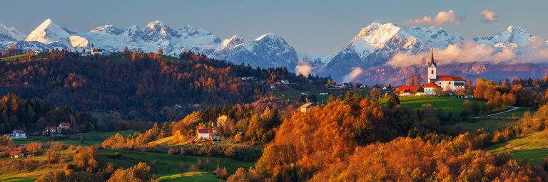 Prezganje and Jance church with snowy Kamnik Alps in the background