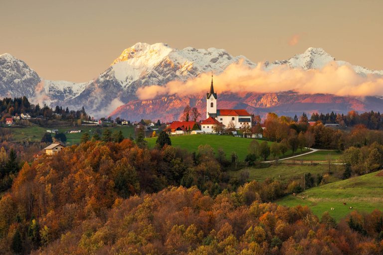 Prezganje church with snowy Kamnik Alps in the background