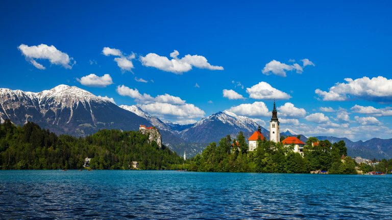 Afternoon view across Lake Bled to the island church of the assumption of saint mary and hilltop castle, Slovenia.