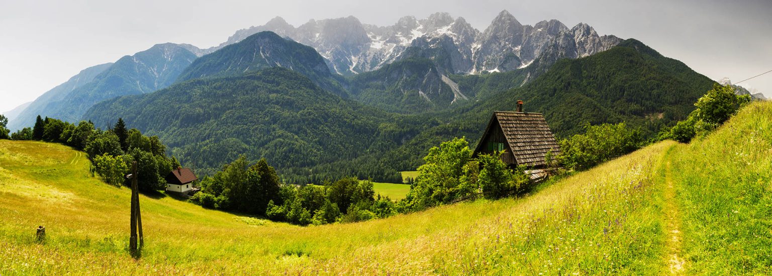 The fairytale cottage in Srednji Vrh village with the Julian Alps behind, near Kranjska Gora, Slovenia