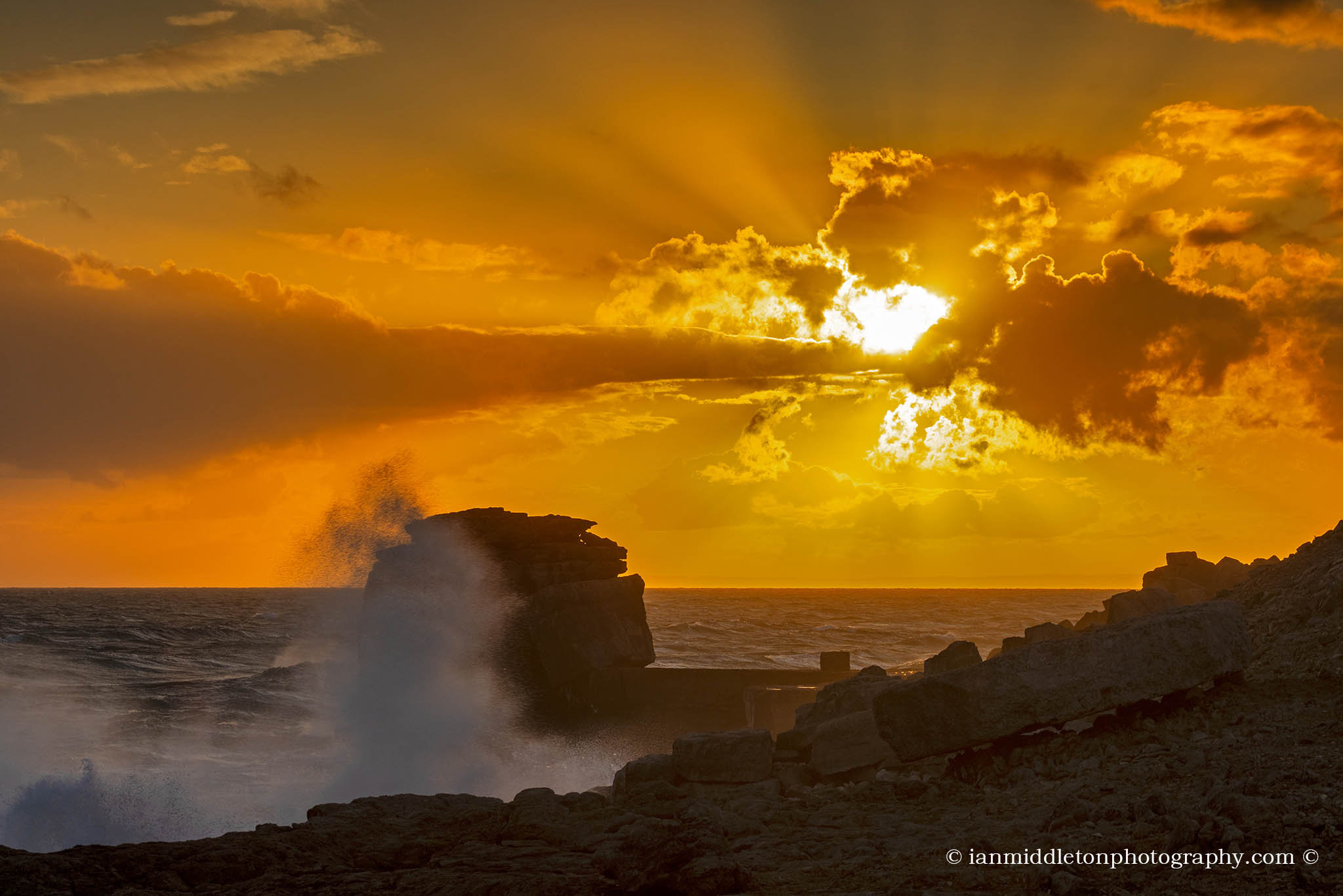 Waves crashing at sunset over Pulpit rock at Portland Bill, near Weymouth, Jurassic Coast, Dorset, England.