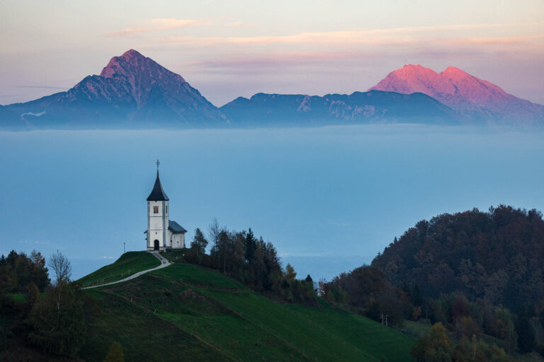 Sunset at Jamnik church of Saints Primus and Felician, perched on a hill on the Jelovica Plateau with the kamnik alps and Storzic mountain in the background, Slovenia.