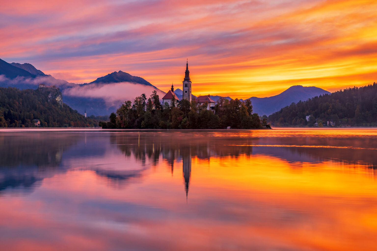 Sun rising over Lake Bled and the island church of the assumption of Mary with the Karavanke mountains in the background, Slovenia.