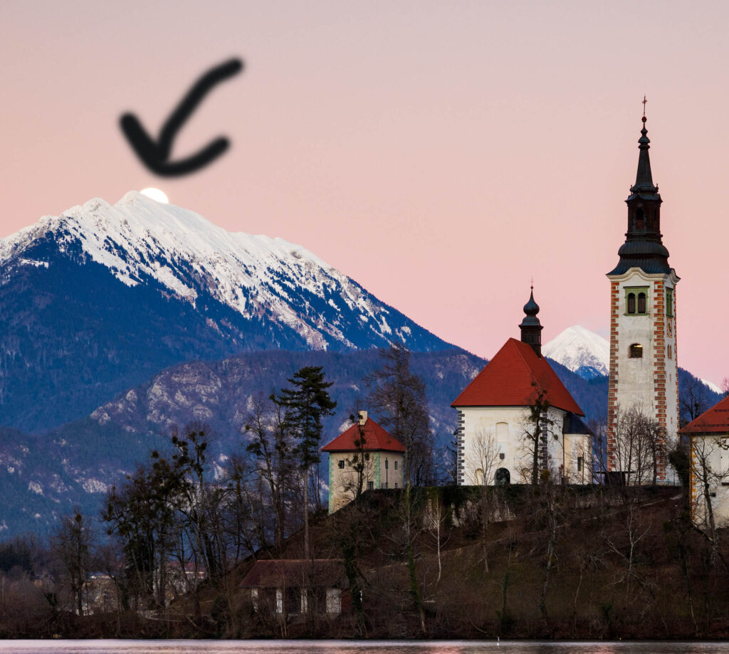 Full moon (January Wolf Moon) rising over Veliki Vrh mountain peak at sunset beside the island church at Lake Bled, Slovenia. Taken on 13th January during the major lunar standstill of 2025