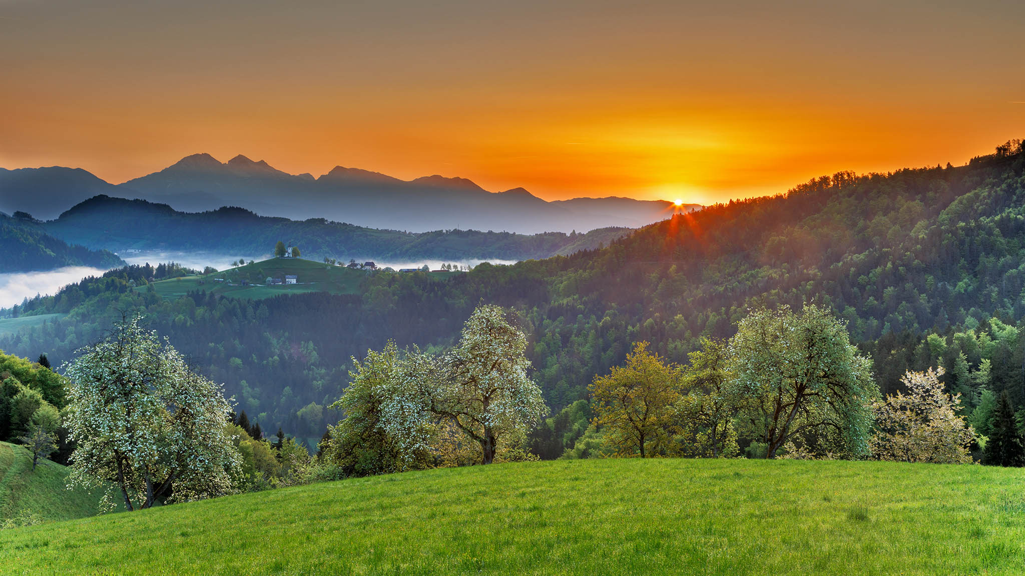 Spring view at sunrise from Rantovše hill across to Sveti Tomaz nad Praprotnim (church of Saint Thomas) and the Kamnik Alps, Slovenia.