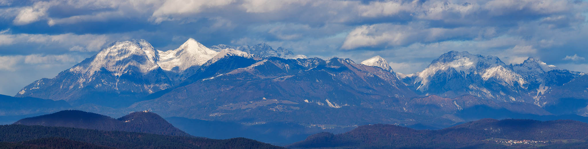 View across to the Kamnik Alps, Slovenia. Cropped from a stitched panorama made from 7 photos. Some prominant mountain peaks from left to right are Kočna, Grintovec, Skuta, Zahodni Vrh, Lučka Baba, Ojstrica. You can also see the Church of Mary on Šmarna Gora, just below Grintovec and Kočna.